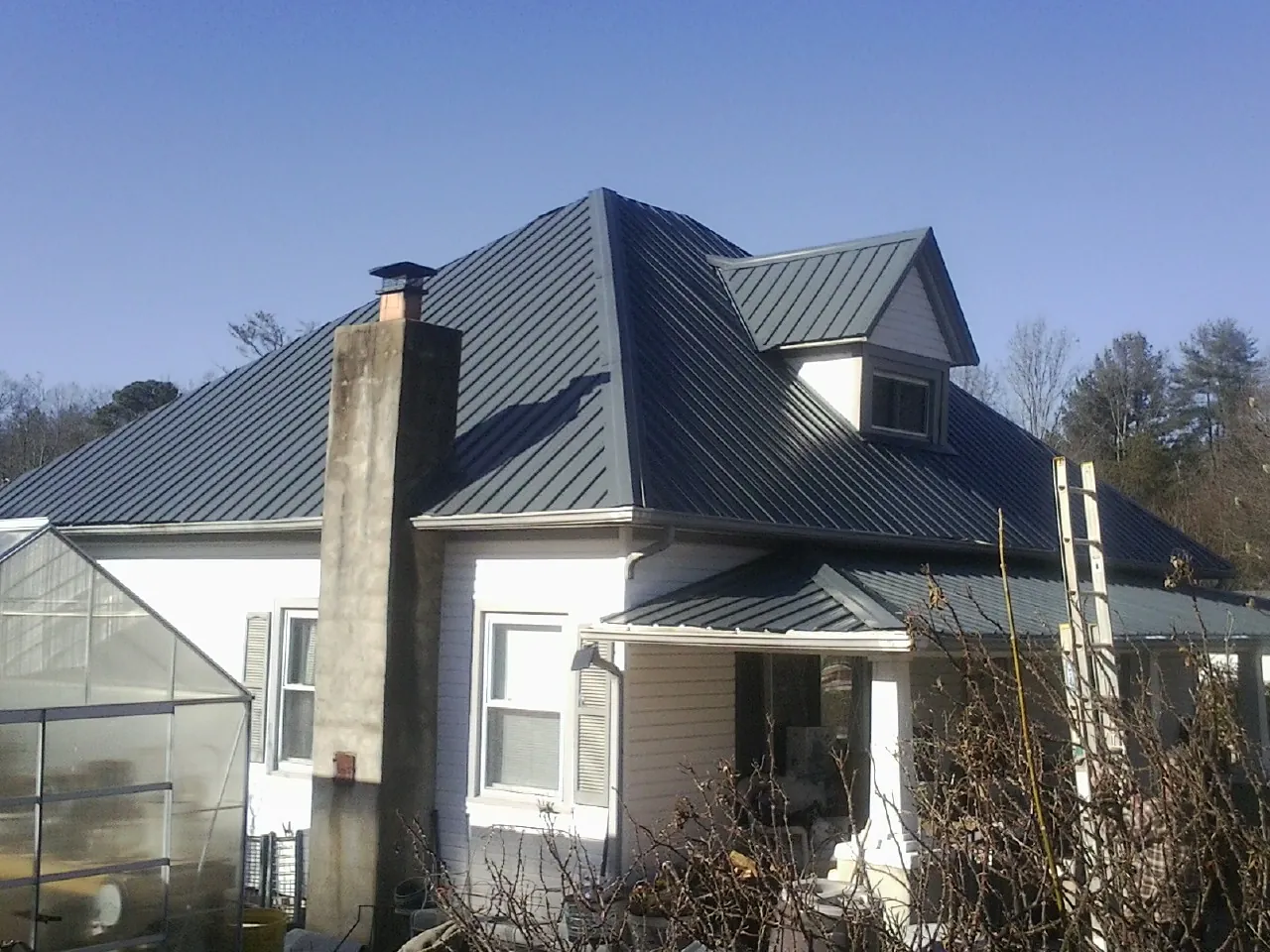 Dark blue standing seam metal roof on a white farmhouse with dormer — Slate & Tile Roof Repair by Roofing Brothers in Sutton
