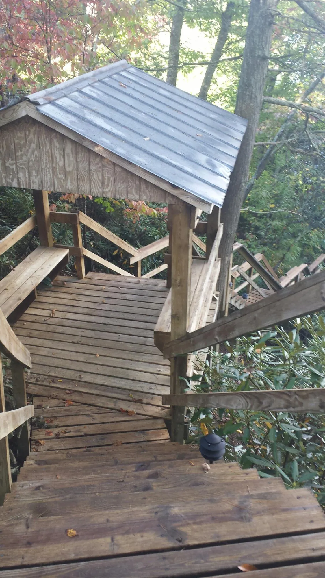 Metal roofed shelter over wooden steps on a wooded walkway — Skylight Repair & Installation work by our crew in Sutton