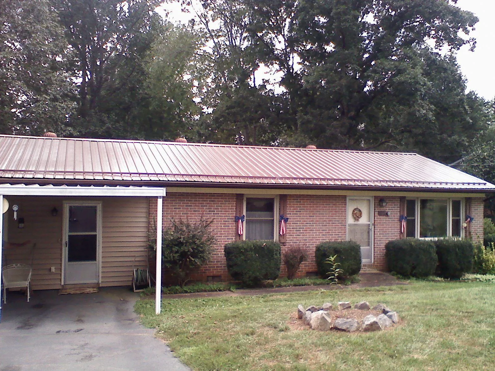 Bronze metal roof and carport on a brick ranch home — Roof Repair work by our crew in Sutton