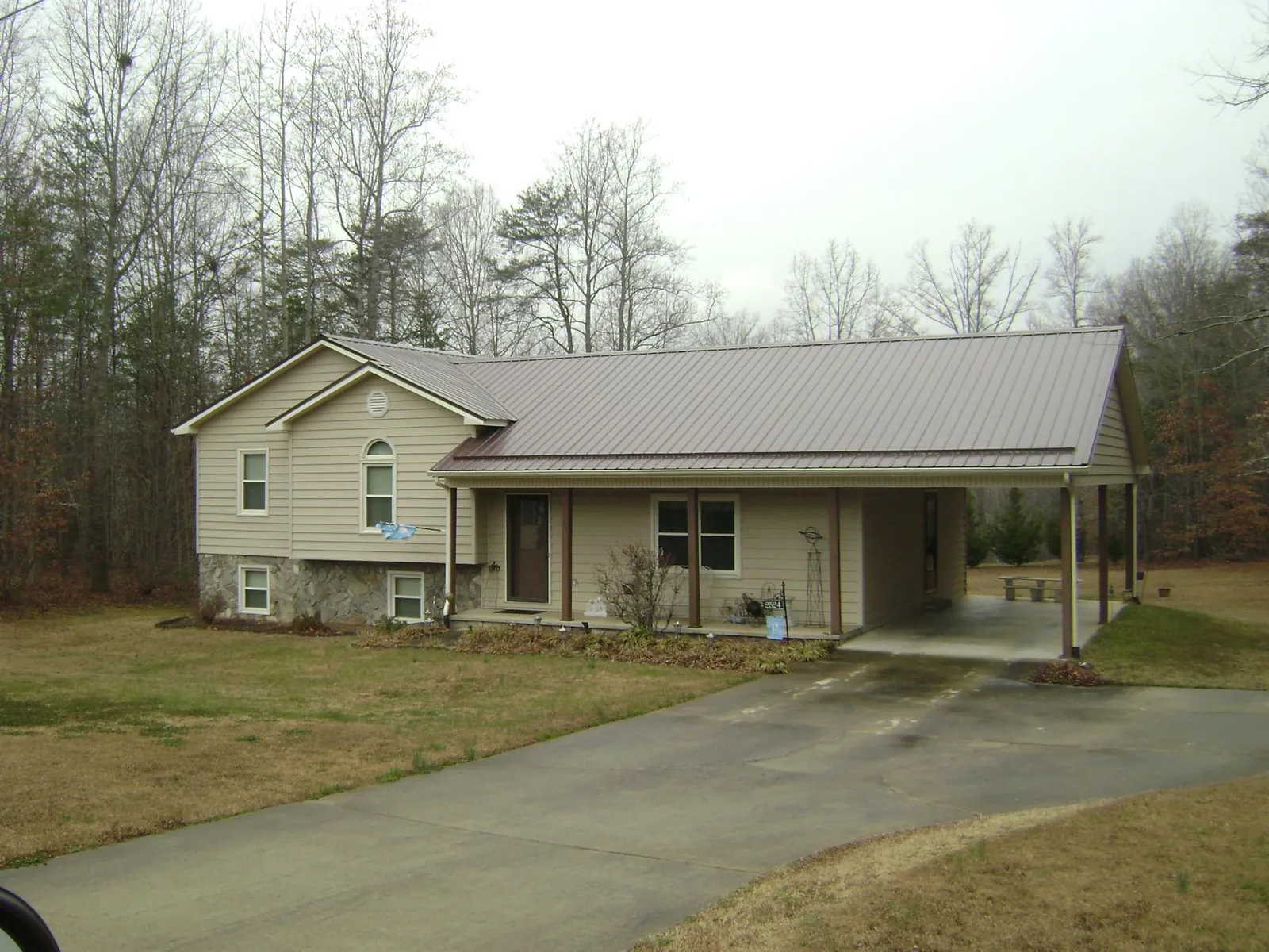 Brown metal roof on a tan split level home with an attached carport in Sutton