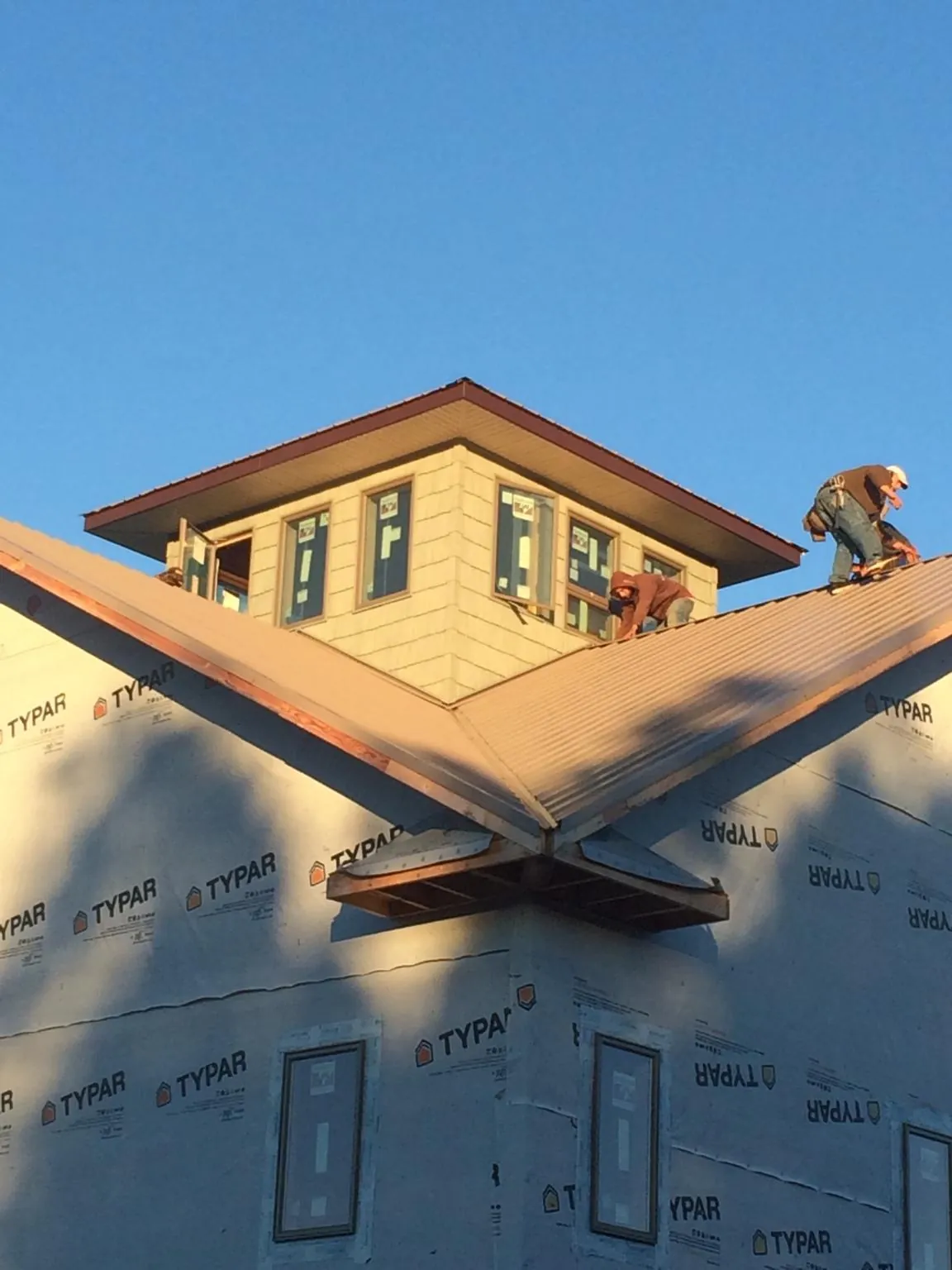 Roofers working around a rooftop cupola on a new metal roof at sunset — Roof Waterproofing in Sutton by Roofing Brothers